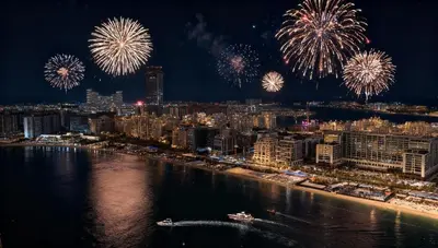 a city with fireworks exploding in the sky over the water at Coastal Chic at Emaar Beachfront 1BR in Dubai
