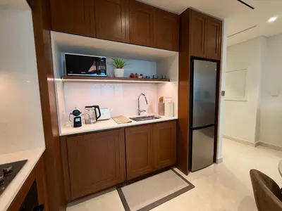 a kitchen with wooden cabinets and a refrigerator at Coastal Chic at Emaar Beachfront 1BR in Dubai