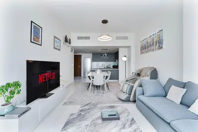 a living room with a blue couch and a table at Beachside Bliss With Stylish 2BR with Panoramic View in Dubai