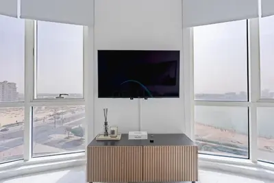 a living room with large windows with a large television at Lake-View Apartment Near City Centre Meaisem Mall, Just Minutes from Dubai Autodrome and ICC Cricket Stadium - The Crescent A, Dubai Production City by Deluxe Holiday Homes in Dubai