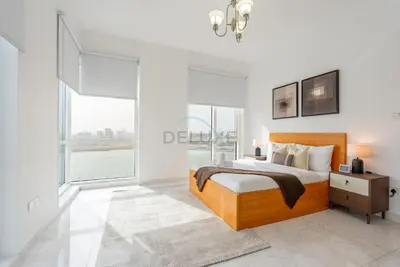 a bedroom with a bed and large windows at Lake-View Apartment Near City Centre Meaisem Mall, Just Minutes from Dubai Autodrome and ICC Cricket Stadium - The Crescent A, Dubai Production City by Deluxe Holiday Homes in Dubai