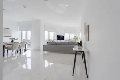 a white living room with a couch and a table at Lake-View Apartment Near City Centre Meaisem Mall, Just Minutes from Dubai Autodrome and ICC Cricket Stadium - The Crescent A, Dubai Production City by Deluxe Holiday Homes in Dubai