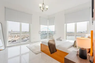 a bedroom with a bed and large windows at Lake-View Apartment Near City Centre Meaisem Mall, Just Minutes from Dubai Autodrome and ICC Cricket Stadium - The Crescent A, Dubai Production City by Deluxe Holiday Homes in Dubai
