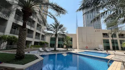 a swimming pool with palm trees and a building at Luxury 2BR in Downtown w Iconic Burj Khalifa View Burj Views 303 in Dubai