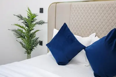 a bed with blue and white pillows and a plant at Luxury 2 BR in Al Barsha Opalz Danube by dpie A312 in Dubai