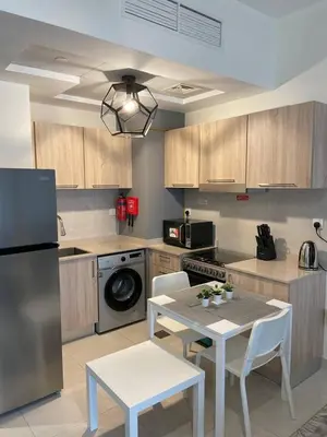 a kitchen with a table and chairs and a refrigerator at Convenient studio in the centre of Dubai in Dubai