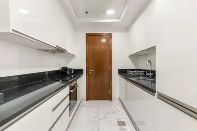 a kitchen with white counters and a wooden door at ALiving Luxury 1BR Apartment with City View I Amna Tower, Al Habtoor City in Dubai
