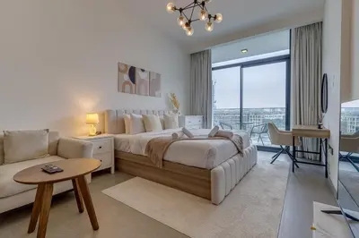 a white bedroom with a large bed and a couch at Oxford Terraces, JVC - Studio Apartment - Allsopp & Allsopp in Dubai
