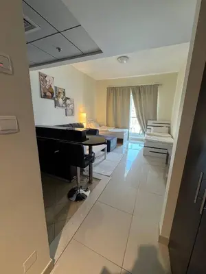 a living room with a piano and a room with a couch at Modern Studio Apartment in Dubai Sports City in Dubai