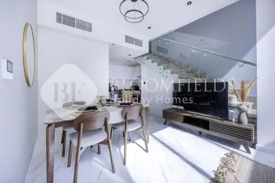 a dining room with a table and chairs and a fireplace at Bloomfields Deluxe 1br Rukan in Dubai