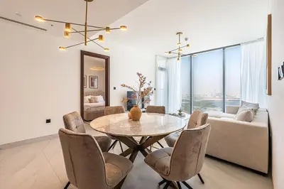 a living room with a table and chairs and a couch at Elegant 2-Bedroom Apartment with Stunning City and Water Views in Dubai