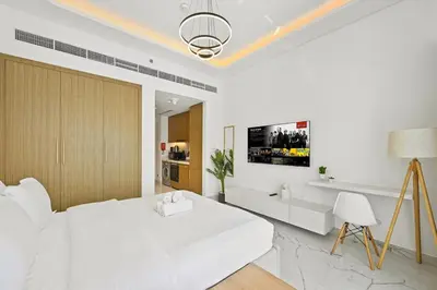 a white bedroom with a large bed and a chair at Estudio Noor en Dubai Por beBalmy in Dubai