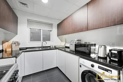 a kitchen with white cabinets and a washer and dryer at Luxurious 3BR Villa Getaway in DH2 by Deleguest in Dubai