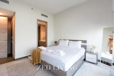 a white bedroom with a white bed and a mirror at Sol Bay - Stay in style with Burj Khalifa views - Zed Living in Dubai
