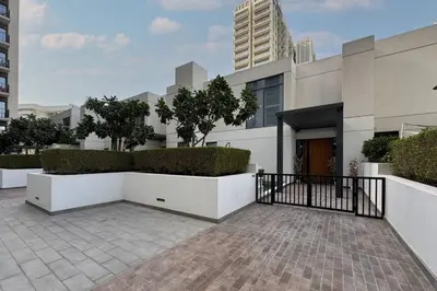 a building with a fence and some bushes at Dubai Hills Townhouse in Dubai