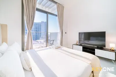 a white bedroom with a large window and a tv at Elz Residence Stylish Studio Living in Dubai