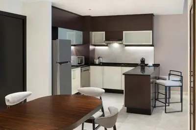 a kitchen with a wooden table and white cabinets at Vintage Grand Hotel Apartments Dubai in Dubai