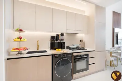 a kitchen with white cabinets and a dishwasher at Vogue JVC Binghatti Dawn near Circle Mall, Studio Apartment with Balcony and Vibrant Community View, Access to all Amenities in Dubai