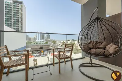 a room with a swing and two chairs on a balcony at Vogue JVC Binghatti Dawn near Circle Mall, Studio Apartment with Balcony and Vibrant Community View, Access to all Amenities in Dubai