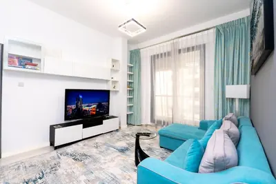 a living room with a blue couch and a tv at Escape24 Elegant 1BR with Marina Views, Dubai Marina in Dubai