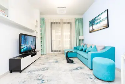 a living room with a blue couch and a tv at Escape24 Elegant 1BR with Marina Views, Dubai Marina in Dubai