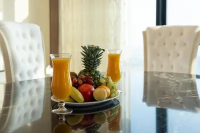 a bowl of fruit on a table with two glasses of juice at Samaya Holiday Homes - Square 1B Duplex Panoramic View in Dubai
