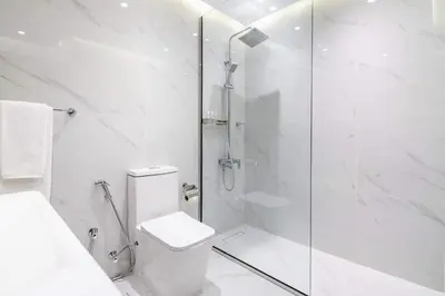 a white bathroom with a shower and a toilet at Frank Porter - Glitz Residence 2 in Dubai