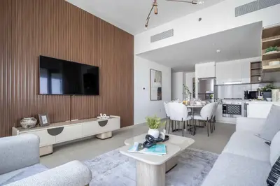 a living room with a couch and a tv on a wall at Frank Porter - Downtown Views II Tower 1 in Dubai