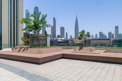 a park with two benches in front of a city at Frank Porter - Downtown Views II Tower 1 in Dubai