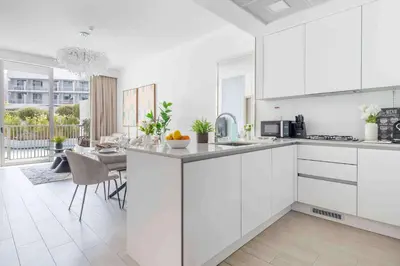 a kitchen with white cabinets and a dining room at Frank Porter - Luma22 West Tower in Dubai
