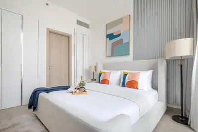 a bedroom with a large white bed with orange and blue pillows at Frank Porter - Luma22 West Tower in Dubai