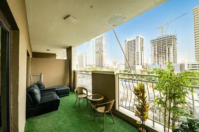 a balcony with a couch and chairs and a view of a city at Escape24 Elegant 1BR in JVC with Pool View in Dubai