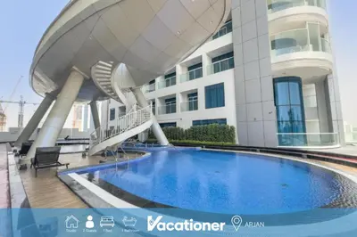 a building with a swimming pool in front of a building at Vacationer I Premium Studio I Pool & Gym Access I Near Miracle Garden I Opalz Tower 2 in Dubai