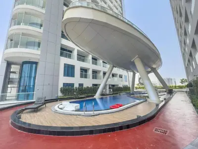 a building with a swimming pool in front of a building at Vacationer I Premium Studio I Pool & Gym Access I Near Miracle Garden I Opalz Tower 2 in Dubai