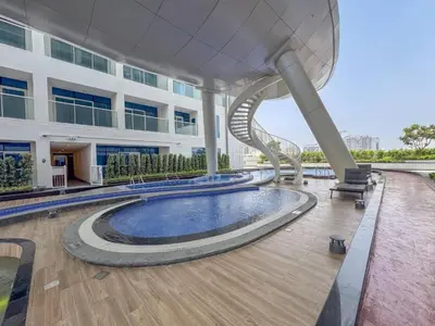 a large building with a swimming pool and a spiral staircase at Vacationer I Premium Studio I Pool & Gym Access I Near Miracle Garden I Opalz Tower 2 in Dubai