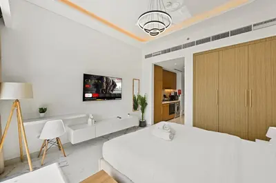a white bedroom with a bed and a tv on the wall at Estudio Rimal en Dubái por beBalmy in Dubai