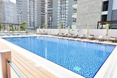 a large swimming pool with chairs and a building at Apartamento Dune en Dubái por beBalmy in Dubai