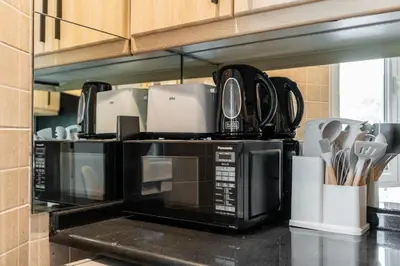 a kitchen with a black microwave oven with utensils at Palmoral Collection Stunning Studio with Dining Area in Dubai