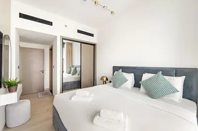 a white bedroom with a large white bed with pillows at VayK - Gorgeous 1BR Retreat in Binghatti Corner in Dubai