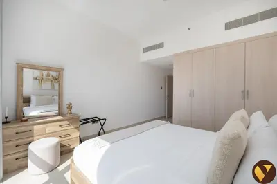 a white bedroom with a large bed and a mirror at Vogue JVC Jeewar Tower near Circle Mall, One Bedroom Apartment with Balcony and Park view, Access to all Amenities in Dubai