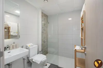 a white bathroom with a toilet and a shower at Vogue JVC Jeewar Tower near Circle Mall, One Bedroom Apartment with Balcony and Park view, Access to all Amenities in Dubai