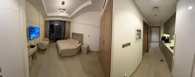 a hallway leading to a room with a bed and a television at Deluxe studio water front in Dubai