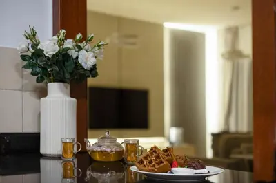 a table with a plate of food and a vase with flowers at JBR Saddaf 4 By Luxe Living - Marina & Sea Views in Dubai