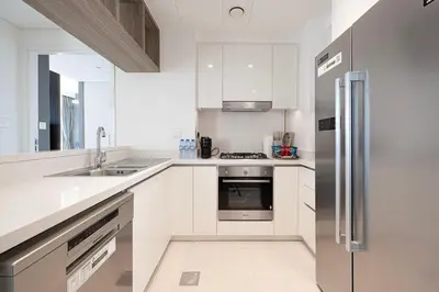 a kitchen with white cabinets and a stainless steel refrigerator at WonderfulStay At Downtown Views II - Best Burj Khalifa View - Direct Dubai Mall Access - Brand New Luxury Apartments in Dubai