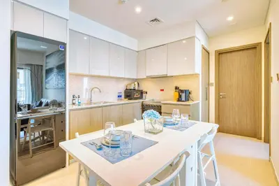 a kitchen with white cabinets and a table with glasses on it at PVH - Charming 1BR near Dubai Mall - Burj Royale in Dubai