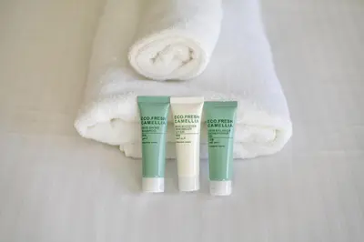two tubes of moisturizing cream next to a pile of towels at Spacious 3BR with Gym & Pool in Royal Residences in Dubai