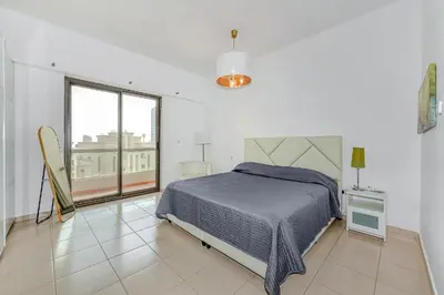 a white bedroom with a bed and a large window at Marina View Relax - Sadaf 1BR Apartment in Dubai