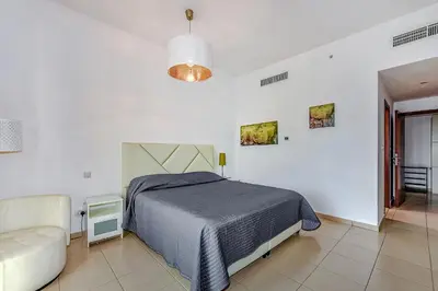 a white bedroom with a bed and a couch at Marina View Relax - Sadaf 1BR Apartment in Dubai