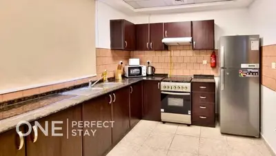 a kitchen with wooden cabinets and a stainless steel refrigerator at 1BR Diamond Views 403A in Dubai