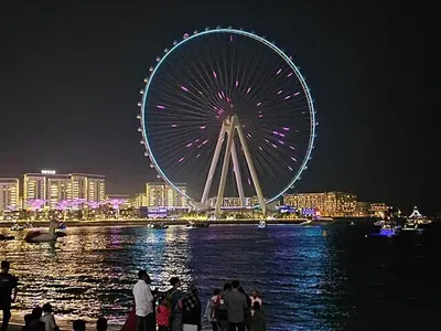 a large ferris wheel in a city at night at Chic waterfront 1 bedroom apartment, walk to beach, promenade, metro in Dubai